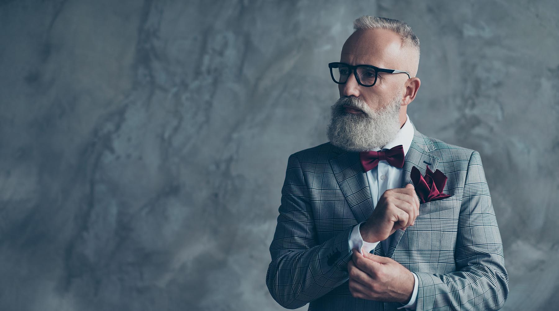 distinguished older man wearing burgundy bowtie and pocket square and gray plaid suit